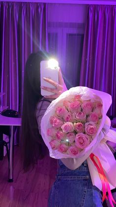 a woman taking a selfie with her cell phone and holding a bouquet of roses