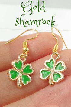 a pair of gold shamrock earrings with green enamel clovers on the front and back