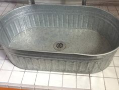 a large metal tub sitting on top of a tiled floor