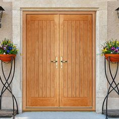 two wooden doors with planters on each side