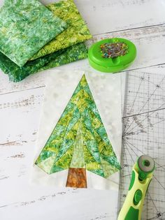 a green piece of cloth next to a pair of scissors and some fabric on a table