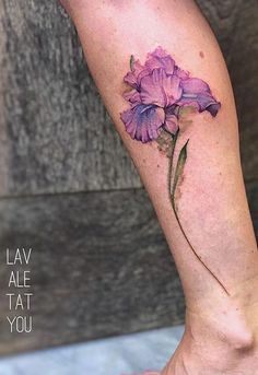 a woman's leg with a purple flower tattoo on her left calf and the words law ale at you written below it