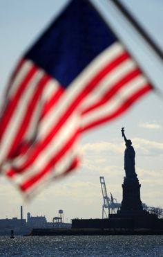 the statue of liberty with an american flag in the foreground and a quote from james monroe