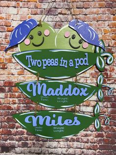 two peas in a pod sign hanging on a brick wall