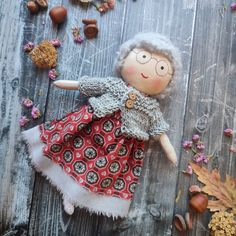 a doll is laying on a wooden surface with nuts and leaves around it, including an acorn