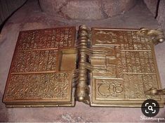 two brass books sitting next to each other on top of a stone slab in front of a rock