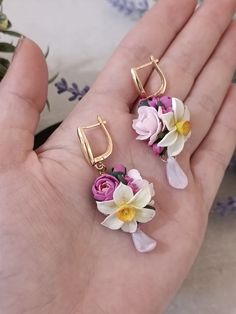 two flowers are attached to the back of small gold hoop earrings, one is pink and white