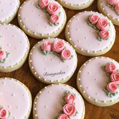 decorated cookies with pink frosting and roses on them sitting on a wooden table top