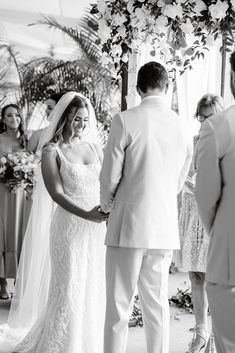 a bride and groom standing at the alter during their wedding ceremony in black and white