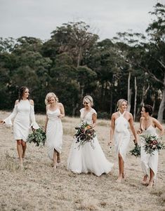 a group of women in white dresses walking across a field