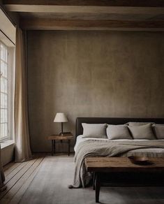 a bed sitting in a bedroom next to a wooden table and lamp on top of a hard wood floor