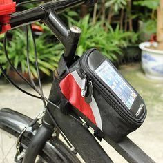 a bicycle with a red and black bag on it's handlebars in front of some plants