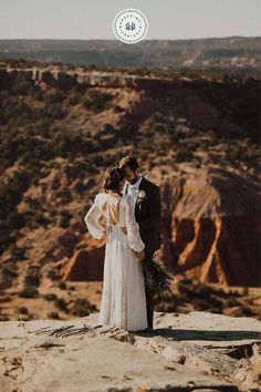 a bride and groom standing on top of a mountain