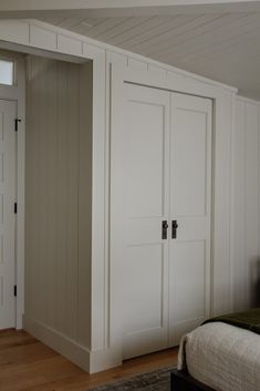 a bed sitting next to a white closet in a bedroom on top of a hard wood floor