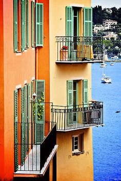 an apartment building with green shutters and balconies on the balcony overlooking water