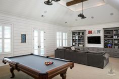 a pool table in the middle of a living room with built - in bookshelves