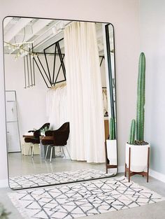 a large mirror sitting on top of a floor next to a chair and table in front of a window