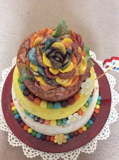 a three tiered cake decorated with gummy bears and a large flower on top