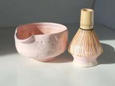 a pink vase next to a white bowl