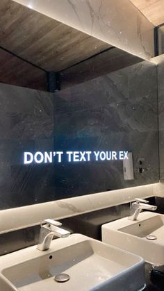 a bathroom with two sinks and a large mirror that says don't text your ex