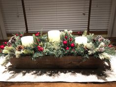 a wooden box filled with candles and greenery on top of a white table cloth