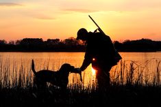 a man and his dog are fishing at sunset