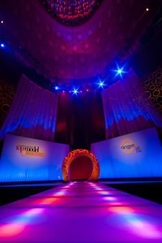 the stage is lit up with purple lighting and blue curtains, as well as bright lights