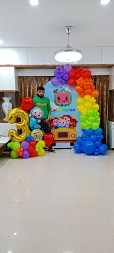 there is a man standing in front of balloons on the floor with numbers and animals