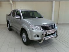 a silver truck is parked in a large room with white tile flooring and walls