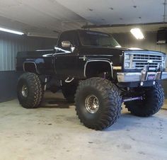 a large black truck in a garage with big tires on it's front wheels