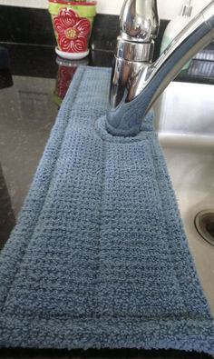 a kitchen sink with a blue rug on the counter and a silver faucet