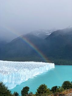 a large glacier with a rainbow in the sky