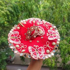 a person holding a red brooch with pearls and other jewelry on top of it