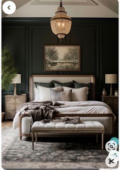 a large bed sitting under a chandelier next to a painting on the wall