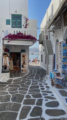 an alley way with shops on both sides and flowers growing out of the top windows