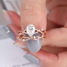 a woman's hand holding an engagement ring with a pear shaped diamond on it