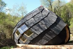 a large black building with windows on top of it's roof in the woods