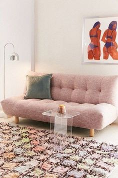 a pink couch sitting on top of a rug in a living room next to a table