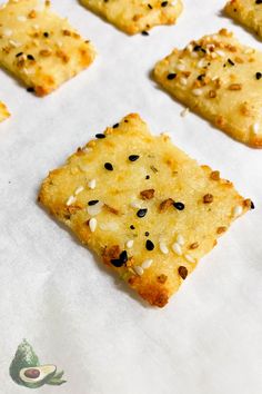 crackers with sesame seeds and seasoning on top are lined up on a baking sheet