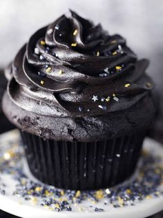 a cupcake with chocolate frosting and sprinkles on a white plate