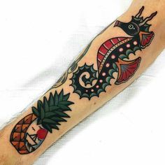 a person with a tattoo on their arm and leg is holding a pineapple in the shape of a dragon