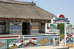 an artisticly designed building with thatched roof and colorful tiles on the outside wall