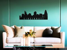 a living room with couches and pillows in front of a city skyline wall decal