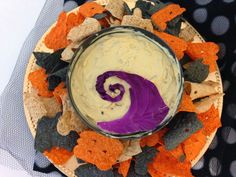 a bowl filled with dip surrounded by crackers and halloween decorations on top of a plate