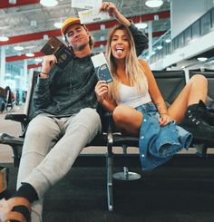 a man and woman sitting on a bench at an airport with their feet up in the air