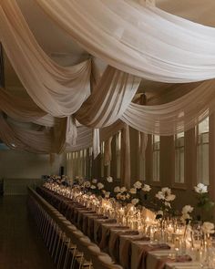 a banquet hall with tables covered in white draping and flower centerpieces