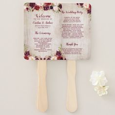 two wooden spats with flowers on them next to a white flower and wedding program