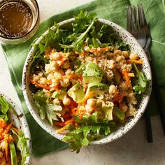 two bowls filled with salad on top of a green table cloth next to silverware