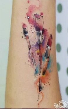 a watercolor tattoo on the leg of a woman's arm with makeup brushes and lipstick