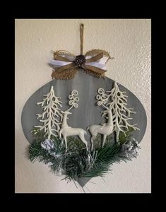 a metal plaque with deer and pine trees on it, hanging from the side of a wall